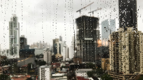 Beautiful view of the raindrops rolling down the window and the skyscrapers in the background